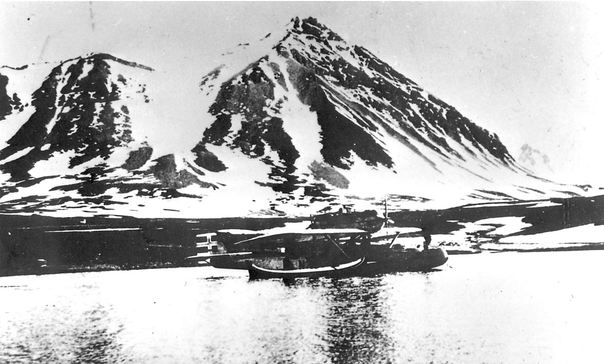 Ett fly, Dornier-Wal, "N-25", fortøyd ute på en fjord, nordlandsbåt ligger foran flyet.
