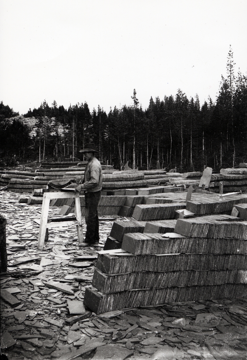 Valdres Skiferbrud. En mann klipper rektangulær skifer med Kollstadsaksa. Tatt rundt 1900.