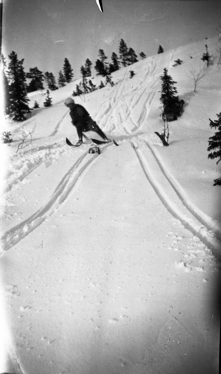 En kvinne på ski i full fart ned en bakke fotografert.

Fotoarkivet etter Gunnar Knudsen.
