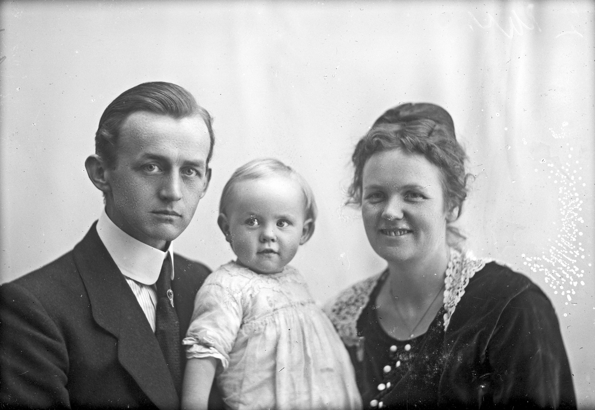 Familiebilde av en far, en mor og et lite barn. Bestilt av Arnold Johnstad.