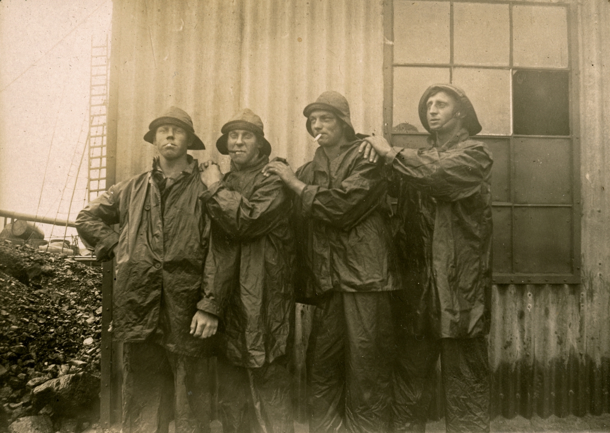 Poserande sjömän iklädda regnkläder. Gustaf Andersson längst till höger.