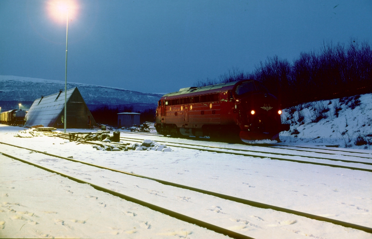 Kveld på Fauske stasjon. NSB dieselelektrisk lokomotiv Di 3 606 utenfor lokomotivstallen.
