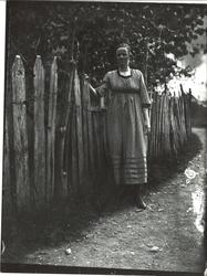 Ung dame poserende ved et gjerde, under et tre.