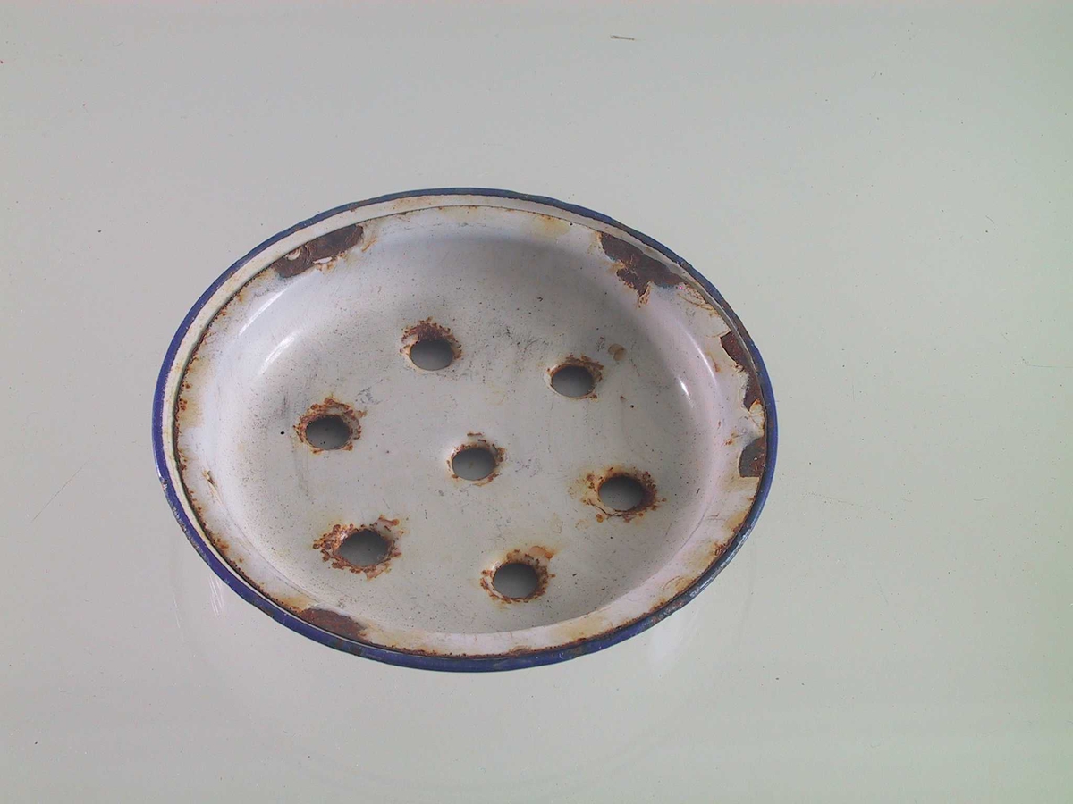 Sepeskål med rist.  Hvitemaljert med blå kant. 
Liten rund skål, inni den en tilsvarende lavere med 7 hull.  
Tilstand: endel skår i cmaljen i kanten.