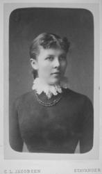 Portrett av en kvinne iført er mørk, tynn genser. Hun har en