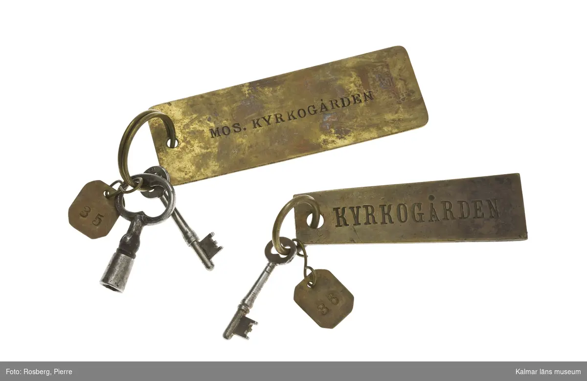 KLM 39266:32:1-2 Nyckelknippor, två stycken, som består av 3 st nycklar till Mosaiska Kyrkogården i Kalmar. :1 en knippa med två nycklar och två tillhörande plåtar med text: Mos. Kyrkogården samt nummer 35. :2 en knippa med en nyckel och två tillhörande plåtar med text: Kyrkogården och Reservnyckel samt nummer 36.