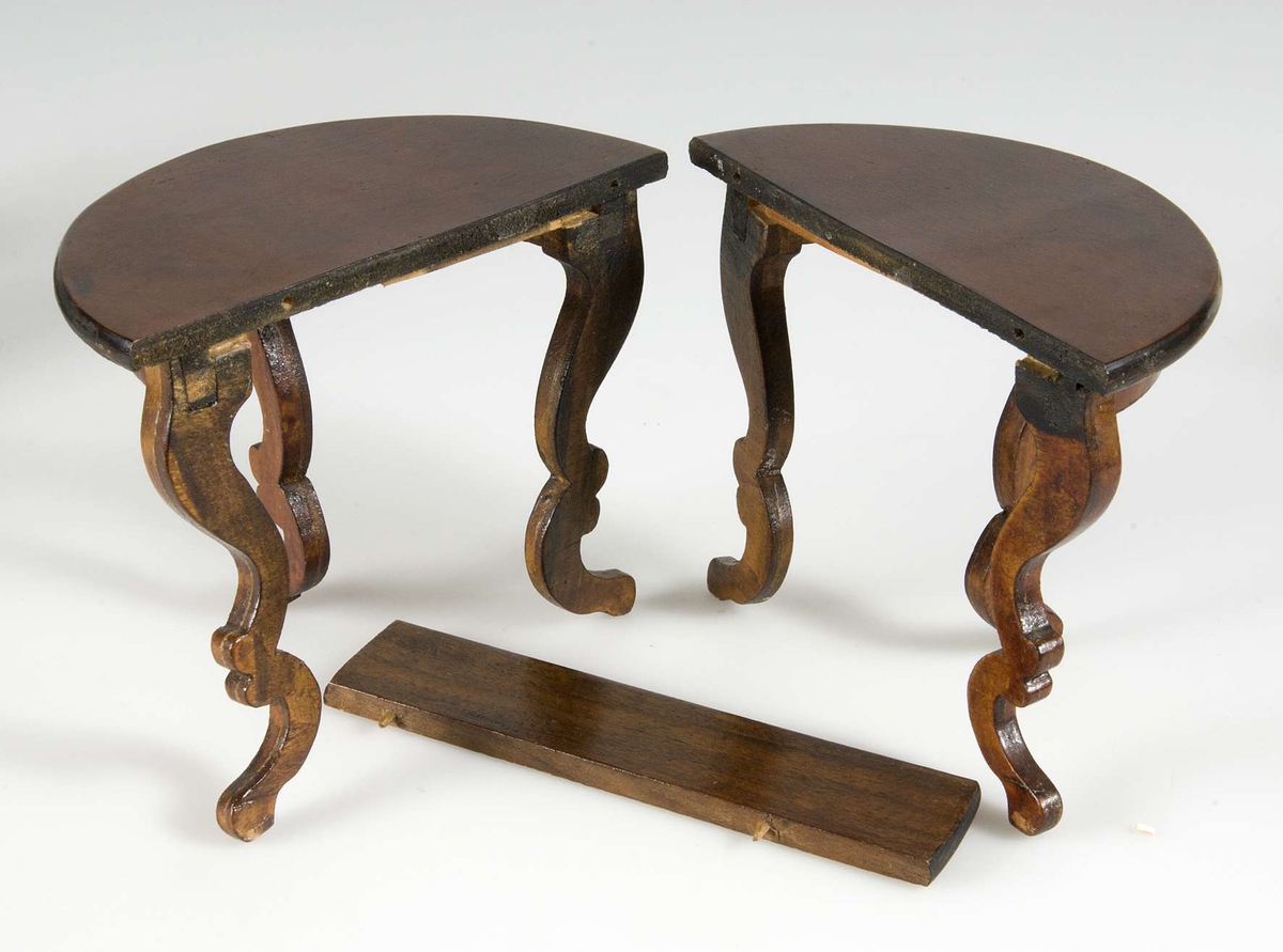 Matbord med svängda ben tillverkat av lackat trä. Till bordet finns en iläggsskiva.