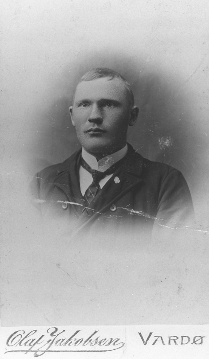Portrett fra en mann, Johannes Ittelin. En liten plastblomst på krage, slips og hvitt skjorte.