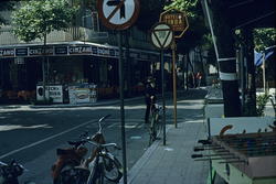 Foto av et gatekryss, mange gateskilt, mopeder og fussballsp