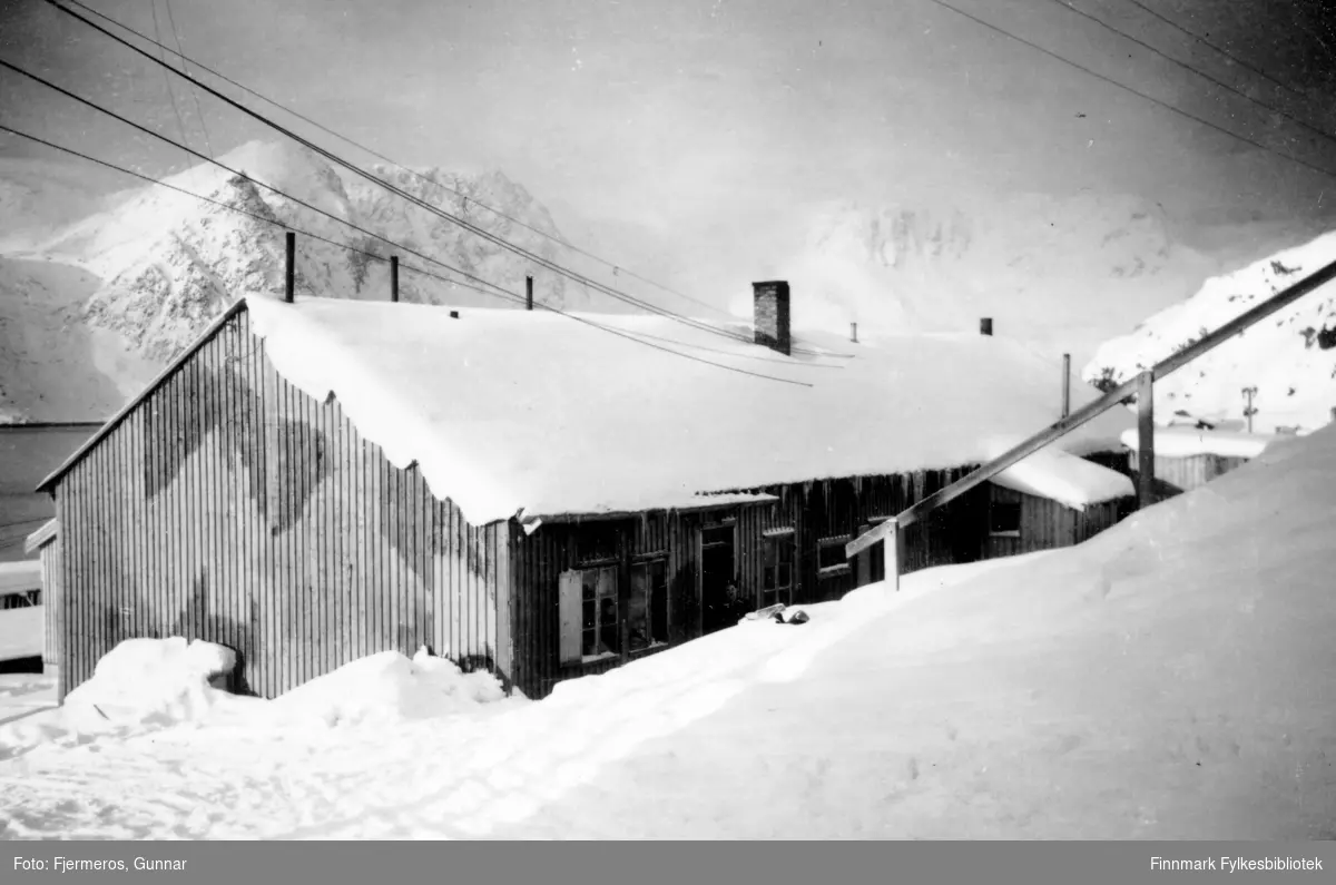 Vinter i Honningsvåg. Fotografi av et gjenreisningshus med mye snø rundt.