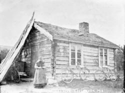 Kvinne foran liten bygning, Magnhilds stue, Lesjaverk, to sy