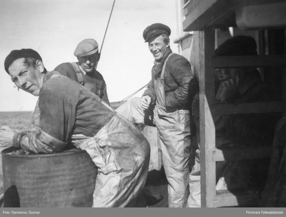 Tre ukjente menn i arbeidsklær står på dekket av en fiskeskøyte under seifisket våren 1948.