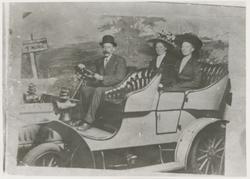 Tre personer i kjøretøy. Ifølge veiskiltet på bakgrunnen kan