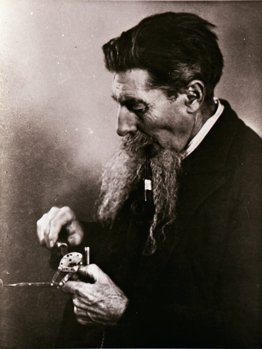 Portrett av en mann som finstiller et instrument/ apparat.