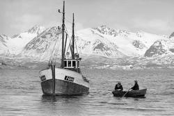 Fiskeskøyte og to menn i en robåt.