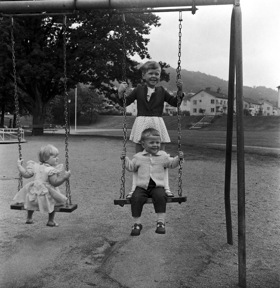 Tre små barn gungar på lekplatsen i Mjölkafållan i Huskvarna.