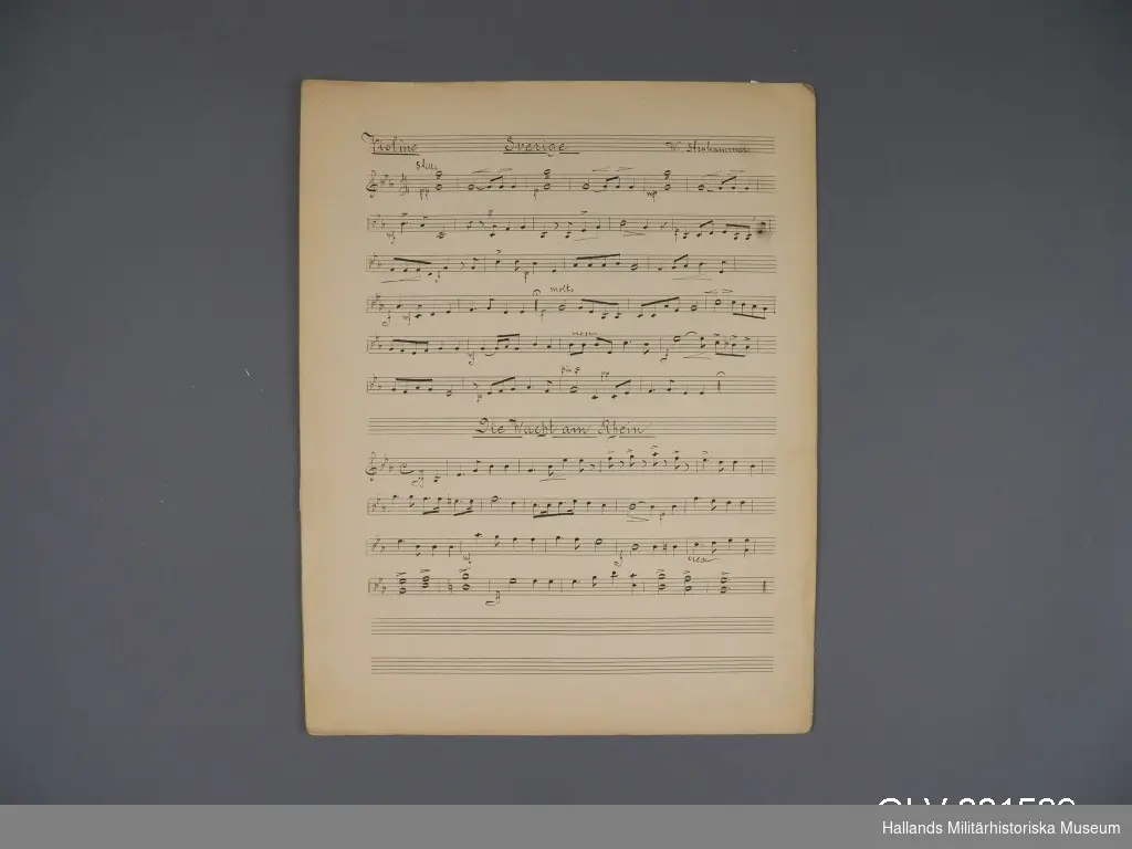 Mappen innehåller handskrivna noter för violinstämman till fyra musikstycken: Sverige av Stenhammar, Die Wacht am Rhein, Grenadjärerna och Marsiljäsen.