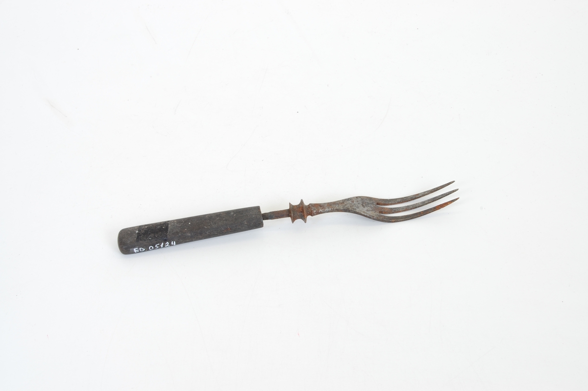 Form: Lang gaffel med tre tinder og treskaft. Stålet øverst på håndtaket har to riller.
