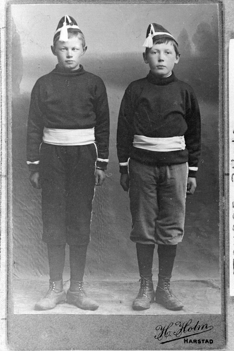 Studioportrett i helfigur av to gutter i en slags uniform.