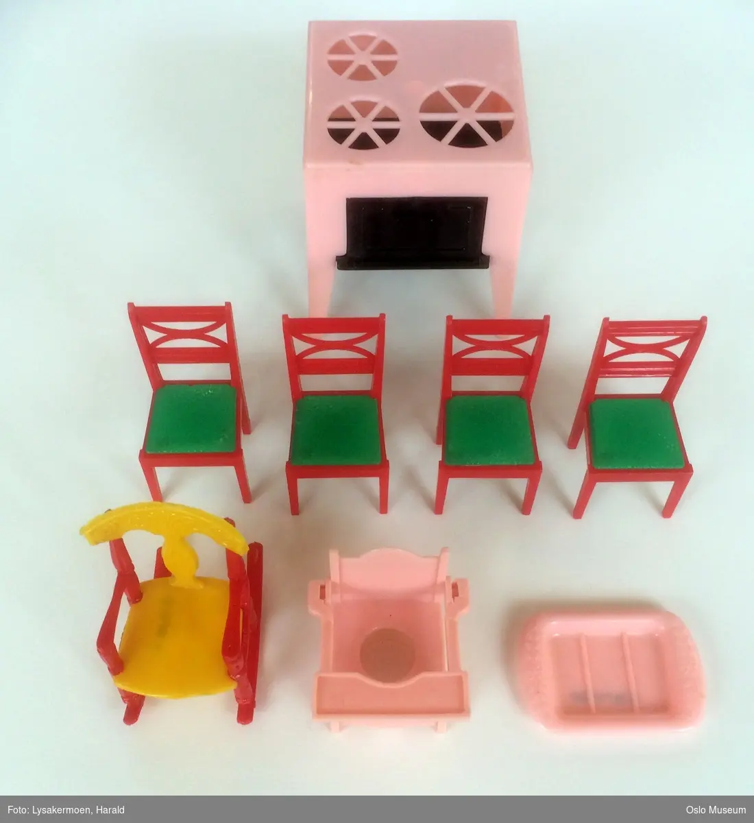 En barnestol med potte, en gyngestol, et serveringsfat, en komfyr og fire spisestuestoler.