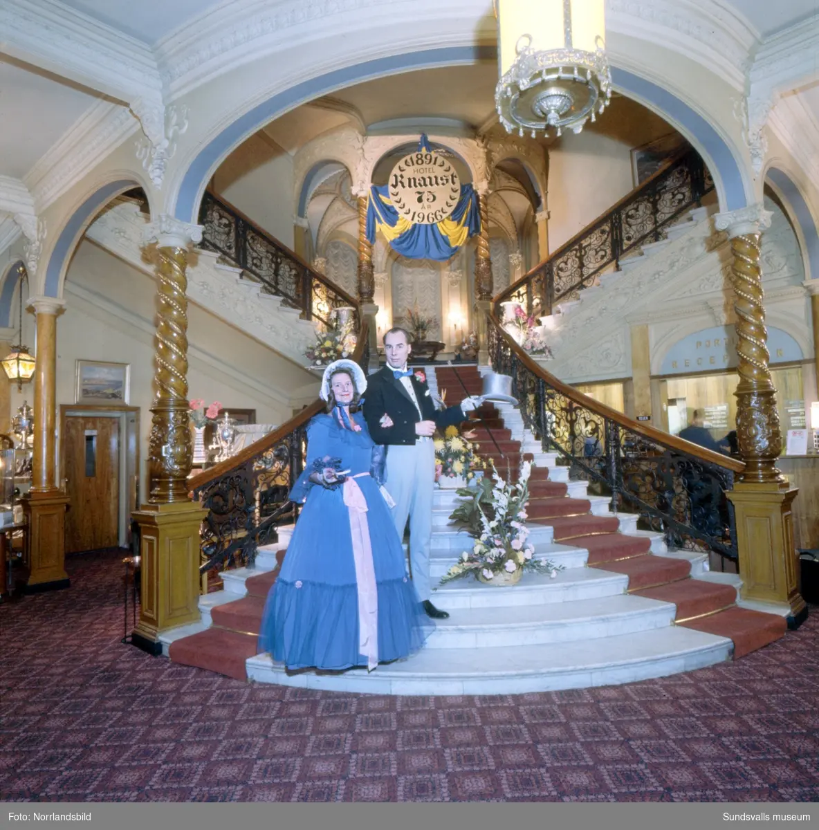 Hotell Knaust firar 75 år och i den berömda trappan poserar ett par i sekelskifteskläder.