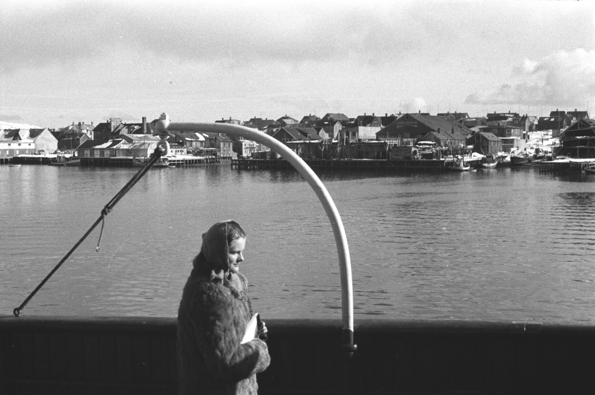Jusstudent Solveig Hanche-Olsen fotografert ombord i Hurtigruta påsken 1947. Havneområdet i bakgrunnen er muligens Vardø havn.

Arkitekt Ola Hanche-Olsen arbeidet ved Brente Steders Reguleringskontor i 1946. Hovedadministrasjon for gjenreisning av Nord-Troms og Finnmark ble lagt til Harstad og fikk navnet Finnmark kontoret. Landsdelen Nord-Troms og Finnmark blev oppdelt i syv distrikt med hver sin administrasjon. Honningsvåg, distrikt IV, skulle betjene Nordkapp, Lebesby, Porsanger og Karasjok kommune.

Ola Hanche-Olsen har tatt bildene. Han var født 13. mars 1920 i Borre, død 11. februar 1998 i Gjettum. Han hadde artium fra 1939, arkitekteksamen fra NTH 1946 og arbeidet deretter ved Finnmarkskontoret 1946–48 før han etablerte egen arkitektpraksis. Han debuterte som barnebokforfatter i 1974 med lettlest-boka "Knut og sjørøverne", og skrev i alt 12 bøker. 

Han var XU-agent 1944-45, og var også en aktiv fjellklatrer og friluftsmann. XU var den største og viktigste allierte etterretningsorganisasjonen i det okkuperte Norge under andre verdenskrig. Det meste av XUs virksomhet ble holdt hemmelig til 1988. Ola var gift med Solveig Hanche-Olsen (f. Falkenberg); de fikk 3 barn, blant dem matematikeren Harald Hanche-Olsen. 

