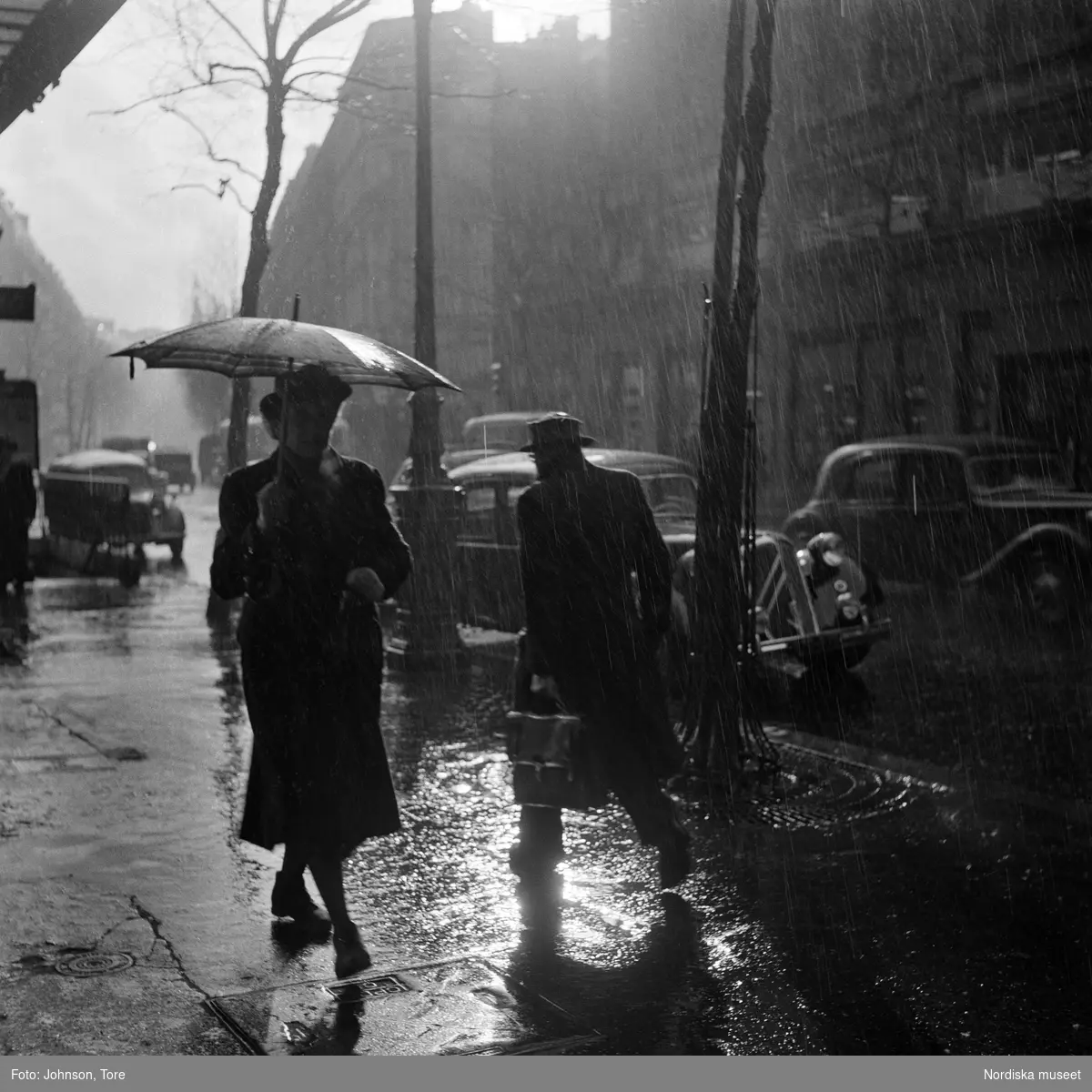 Paris. Fotgängare med paraply på regnig gata.