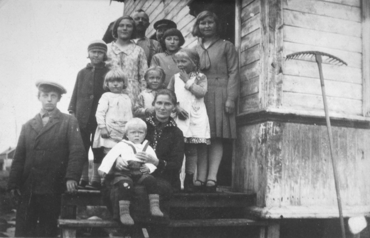 Flere personer poserer på en trapp til et hus som sansynligvis står i Kvalsund kommune før evakueringa. Personene er ukjent, men det er muligens en familie.