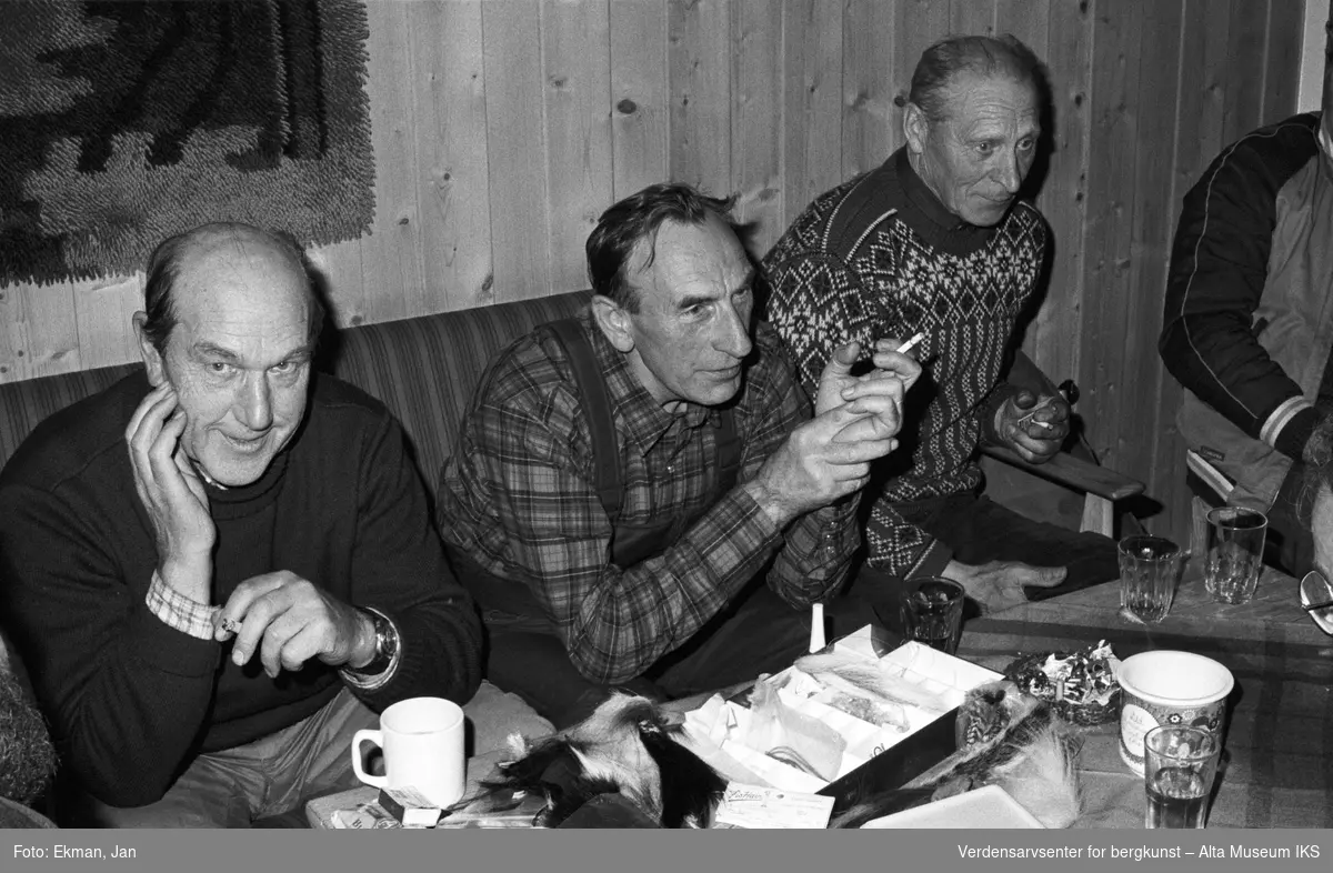 Hytteinteriør med personer.

Fotografert 1982.

Fotoserie: Laksefiske i Altaelva i perioden 1970-1988 (av Jan Ekman).
