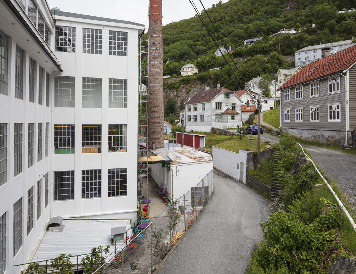 Bygda Salhus utanfor Bergen, med den tidlegare tekstilfabrikken Salhus Tricotagefabrik, fabrikkpipa og ein arbeidarbustad til høgre.