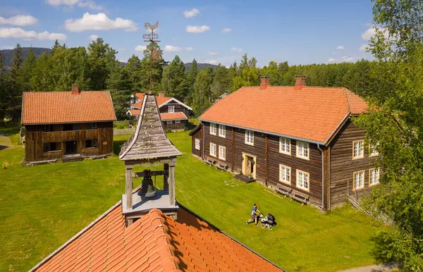 Et bildet av Odalstunet tatt med drone. På bildet ser man tre bygg. På bygget i forgrunnen er det er klokke. Blå himmel og grønt gress.