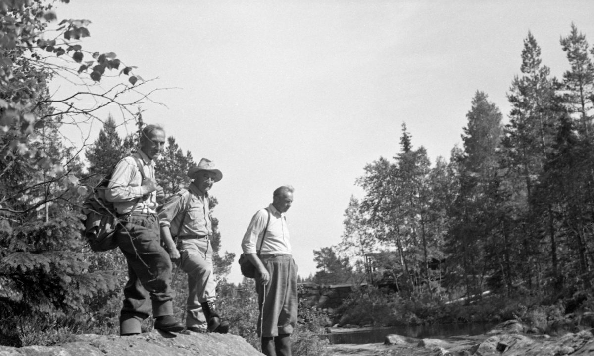 Åbefaring i Juråa i Nord-Odal i 1956.  Det viser tre karer - Hans Engen, G. Hovdenak og Per Mobraaten - ved vassdraget en sommerdag med beskjeden vannføring. Engen og Mobraaten var lokale skogeiere, som antakelig representerte grunneiere ved vassdraget. «G. Hovdenak» kan ha vært Gunnar Hovdenak  (1892-1980), som var disponent i firmaet Westye Egeberg & Co,