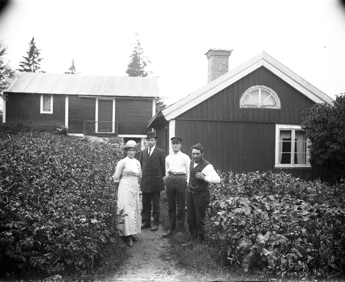 Kvinna och tre män utanför bostadshus.