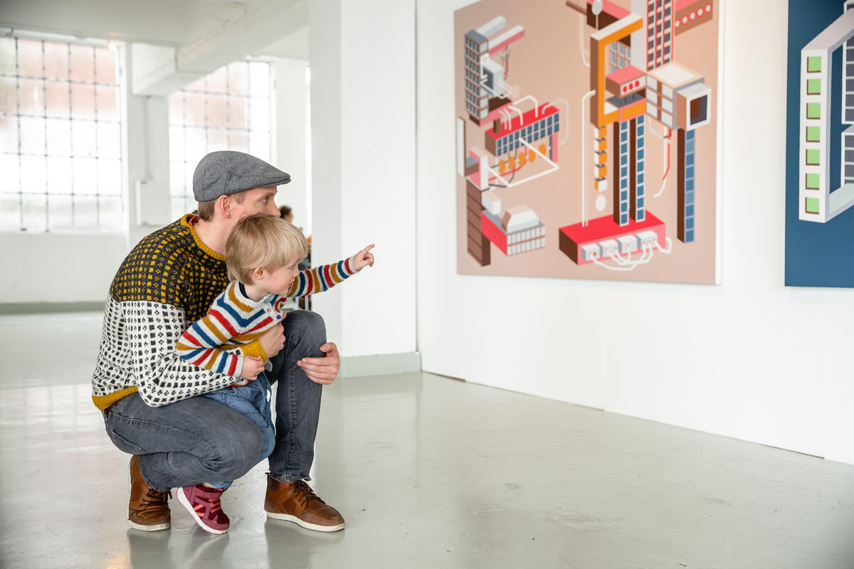 man and boy looks at painting in exhibition space
