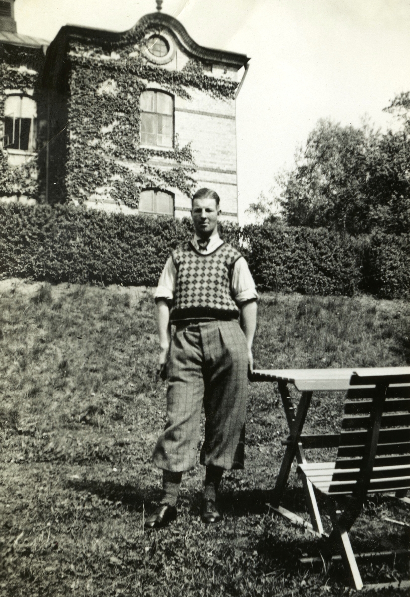 Gustav Berglund står finklädd framför Stora skolan i Stretered, 1930-tal. Han var elev på Stretereds skolhem.