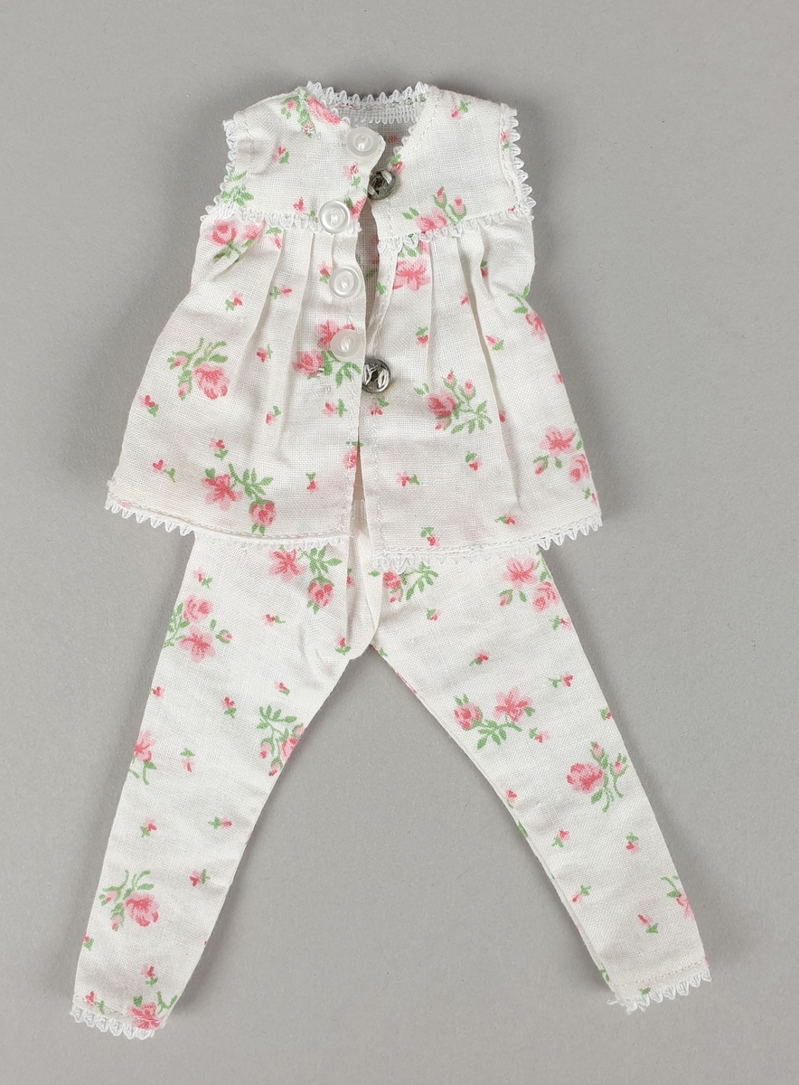 Hvit pysjamas med rosa blomstermønster, bestående av bluse og bukse.