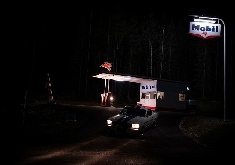 Novembermørket gir en mystisk ramme for øde, opplyst bensinstasjon og bil i mørket. Foto: Morten Reiten/Norsk vegmuseum (Foto/Photo)