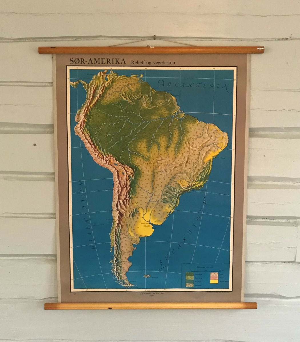 Kart over Sør-Amerika aom viser relieff og vegetasjon. Kartet er trykt på papir og forsterket med pålimt stoff i lerretsbinding bak. Rundstokk både nede og oppe. 