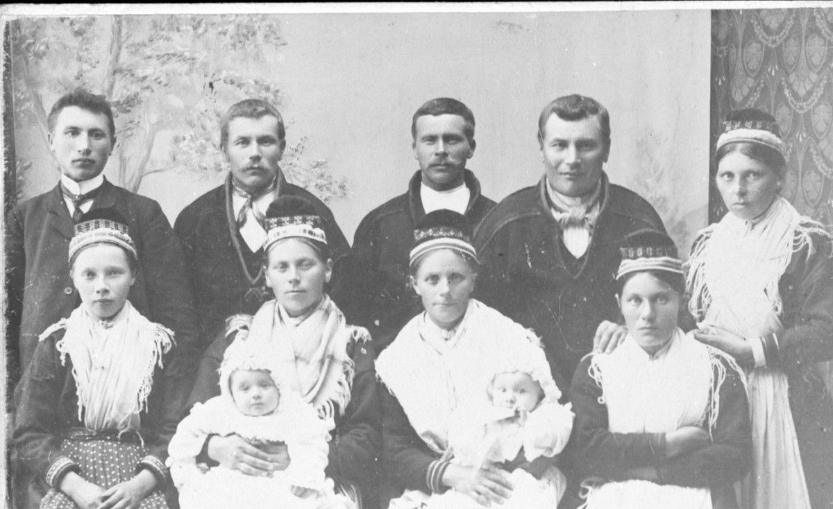 Gruppeportrett av fire menn, fem kvinner og to babyer, flere kledt i samedrakt.