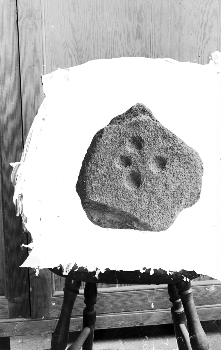"5066 g. Flat sten med 4 skålformede fordypninger på den ene side. Stenens størrelse er 32 x 34 cm., største tykkelse ca. 5 cm. Skålene som er anbragt i en firkant omtrent midt på stenens overflate, har et tverrmål fra 3,5-4,5 cm". 
