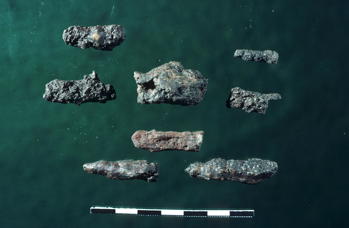 "Tre små jernstifter, 3,2-3,9 cm. l." Ny beskrivelse etter revisjon: Åtte fragmenter av nagler av jern, stl: 39 mm.