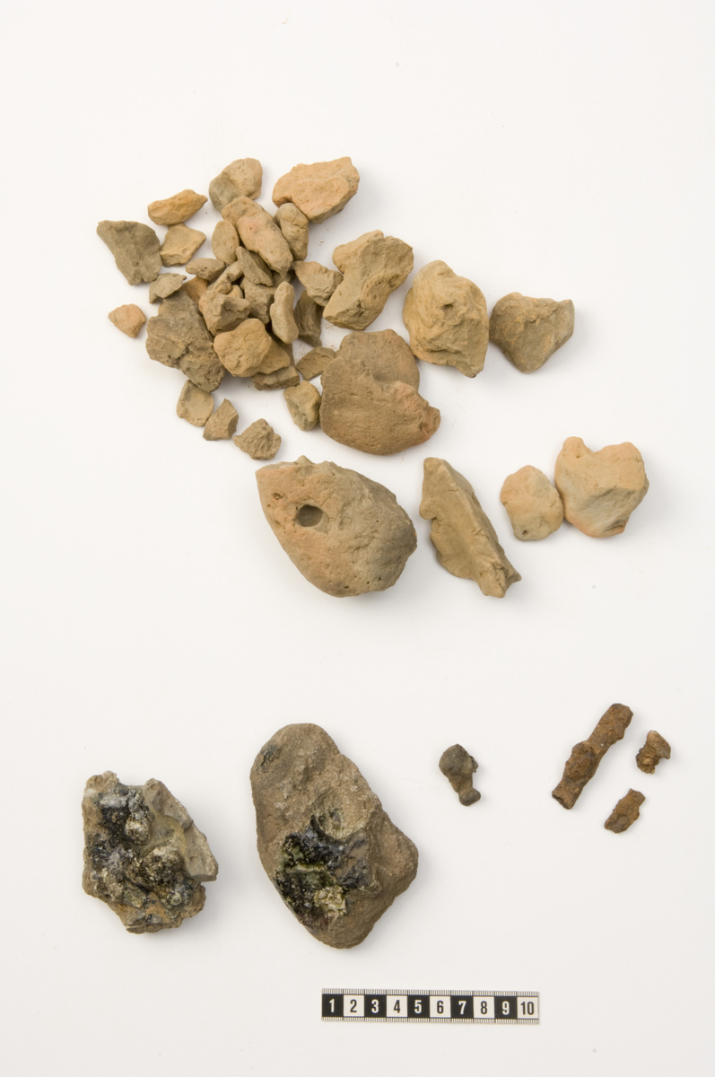Tre fragmenter fra to mulige avlsteiner av hardt brent brunoransje leire. Begge stykkene har mulig avtykk etter blåsebelgtut med diameter på ca 15 mm. 