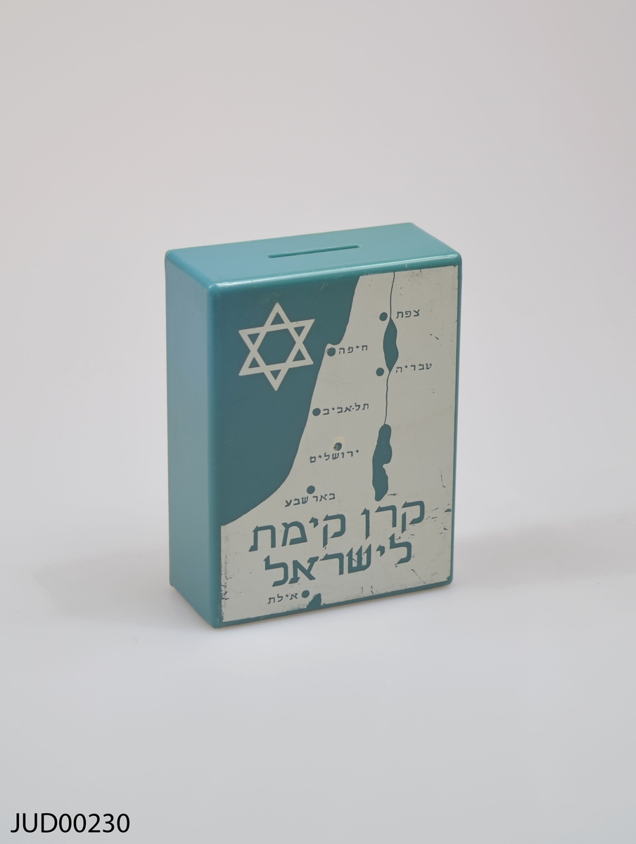 Grönblå insamlingsbössa med vit dekor. Dekorerad med stjärna, karta samt hebreisk text. Knapp fäst på bössan, på vilken det är skrivet med hebreisk text samt nr 05292.