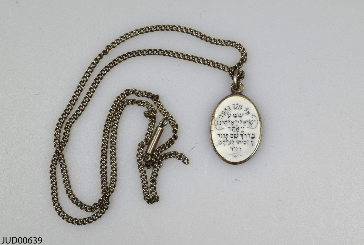 Halssmycke i form av medaljong. Ena sidan är dekorerad med en färgglad Moses som håller i stentavlorna och andra sidan är dekorerad med hebreiska text (shema bönen). Hänger i en lång kedja.