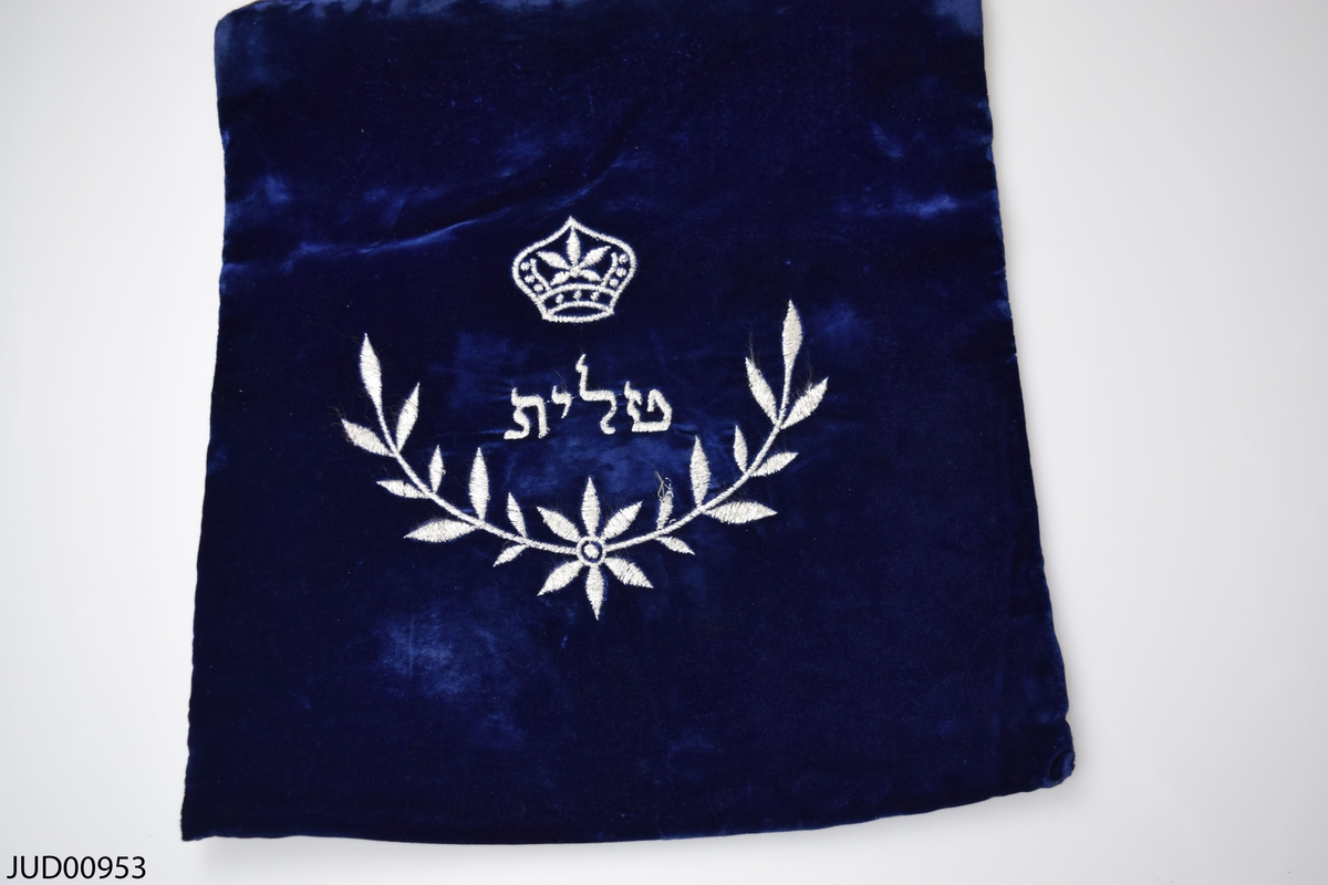 Krona samt blomsterkvist med ordet tallit på hebreiska  i mitten.
