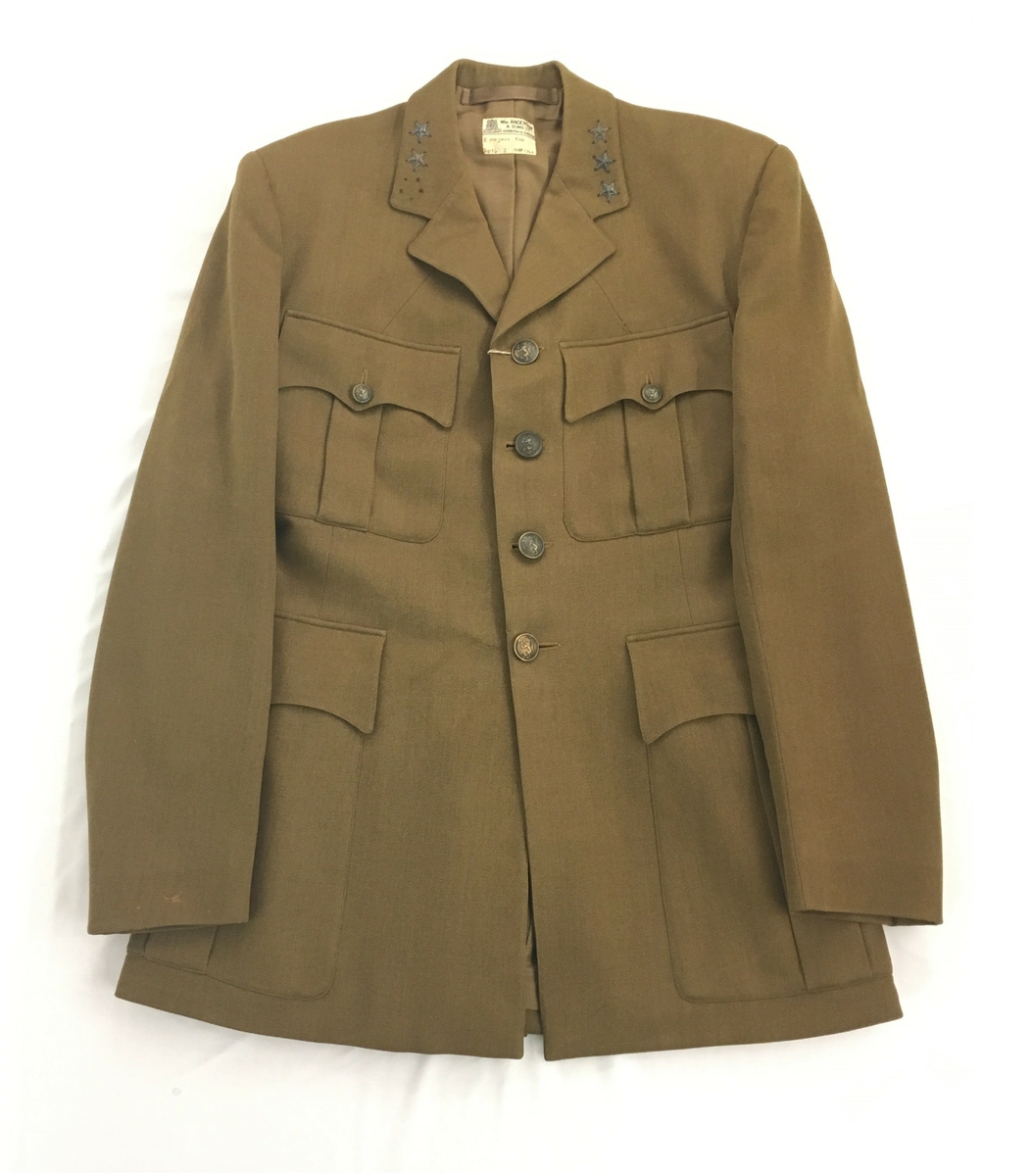 Brun uniform som består av jakke, bukse med belte, hatt og  lærbelte.