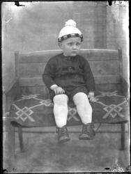 En liten gutt sitter på en krakk.