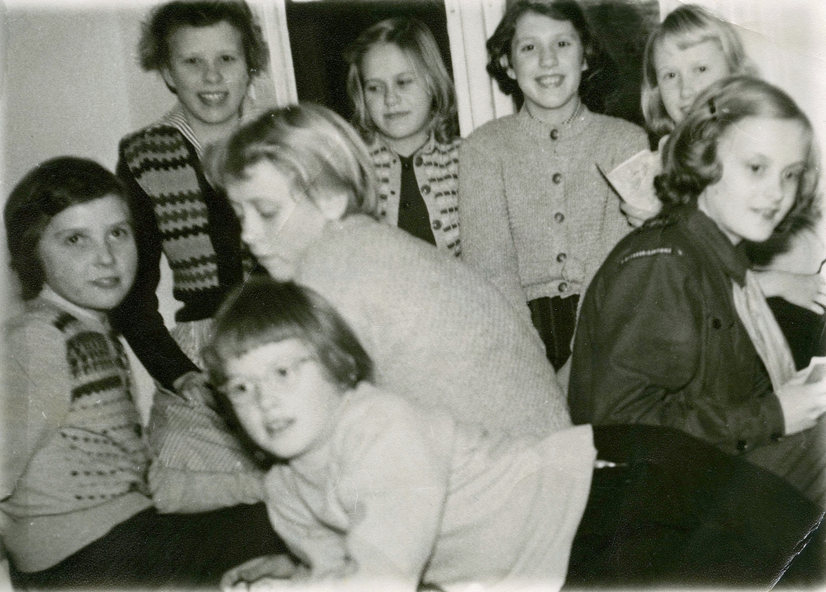Scoutmöte med ungdomar i Brattbergs källare (en villa i Kyrkbacken) år 1952. Längst bak från vänster: 1. Eivor Brattberg, 2. Mona Brattberg, 3. Solveig Svensson Storfors (Vommedal) och 4. Agneta Larsson (Stretered). 
Mellanraden från vänster: 1. Kerstin Axelsson, 2. Gullvi Börjesson, 3. Ingegärd Johansson (Kyrkbacken).
Längst fram: Ingela Levén (Prästbacken).
