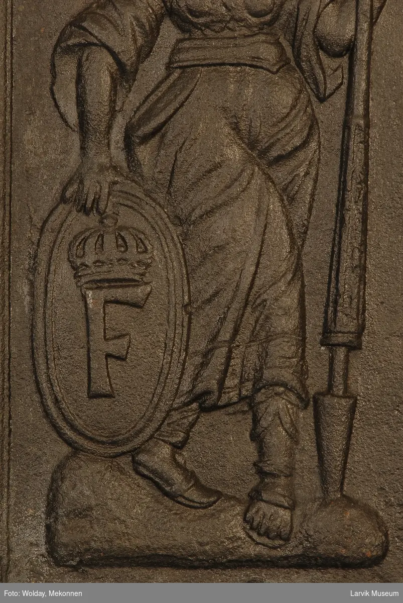 Minerva gående mot høyre med spyd i sin venstre hånd og ovalt skjold med kronet F i høyre hånd