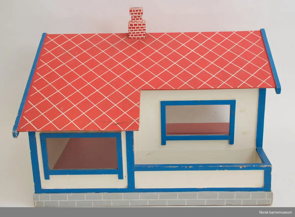 Dukkehuset er utformet som funkishus og har 2 store rom. Taket er skrått med pipe. Taket er malt rødt, med hvite streker som skal symbolisere takpanner. Veggene er hvite, med blåmalte lister rundt de fire vinduene. 